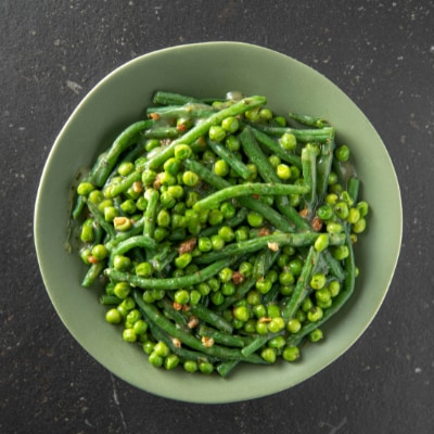 Petits pois et haricots verts avec du lard et de l'oignon